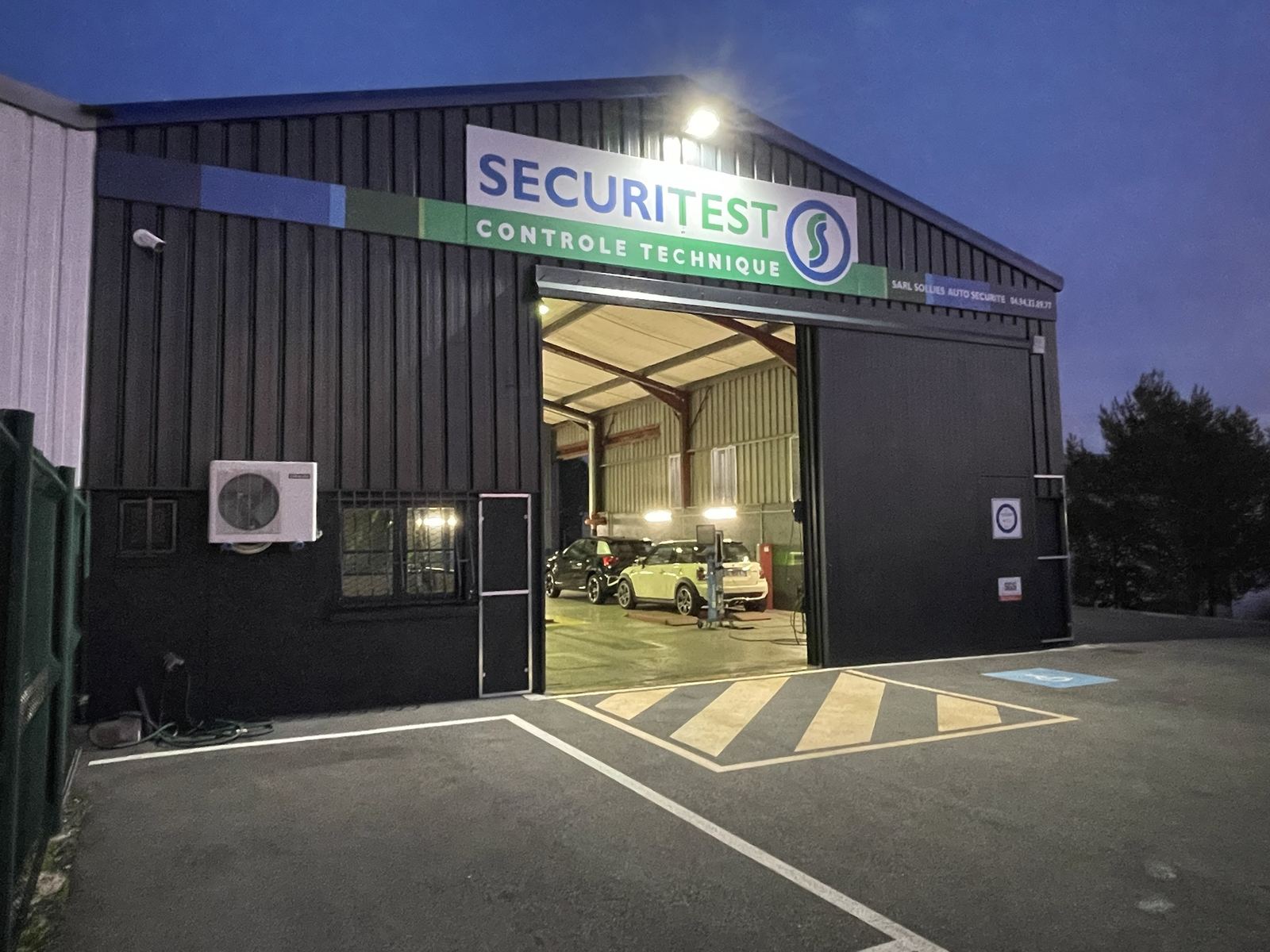 Enseigne Securitest contrôle technique à Solliès-Pont : panneau de façade et bandeau aux couleurs de la marque, de nuit
